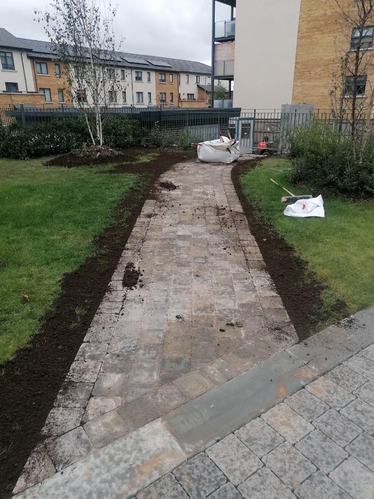 A brick pathway under construction with apartment buildings